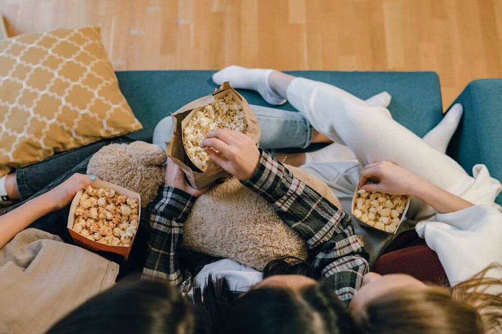 pessoas no sofá comendo pipoca para assistir os melhores filmes de terror da HBO