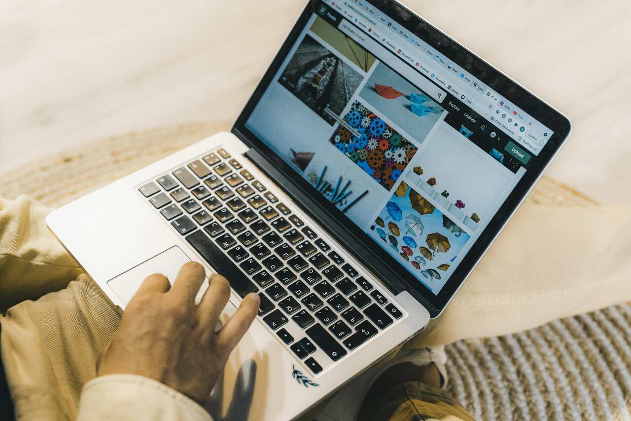 Pessoa usando um notebook com a tela aberta em uma galeria de imagens, navegando por opções coloridas.