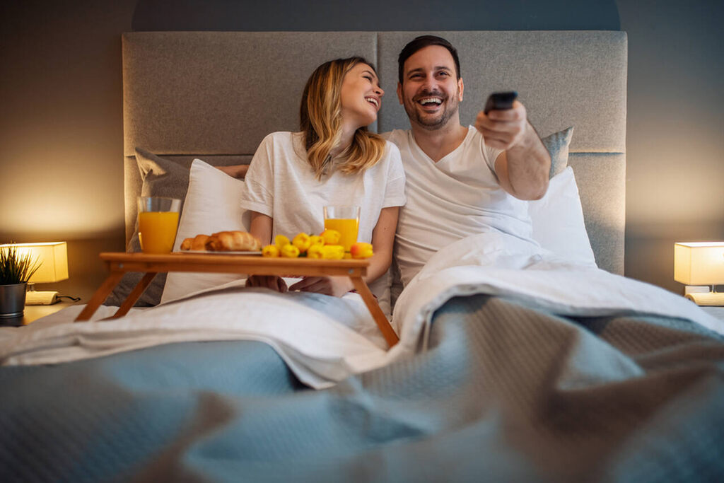 casal assistindo filme na cama, depois de conectar a TV na internet