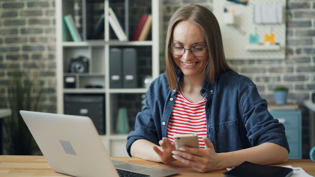 Mulher sorrindo acessando internet Júpiter pelo celular e notebook