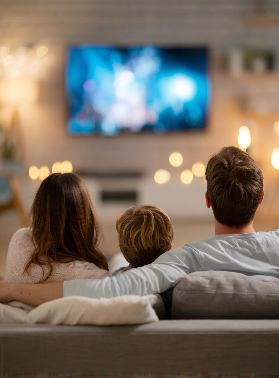 fam&iacute;lia assistindo tv no sof&aacute; em casa com internet residencial est&aacute;vel