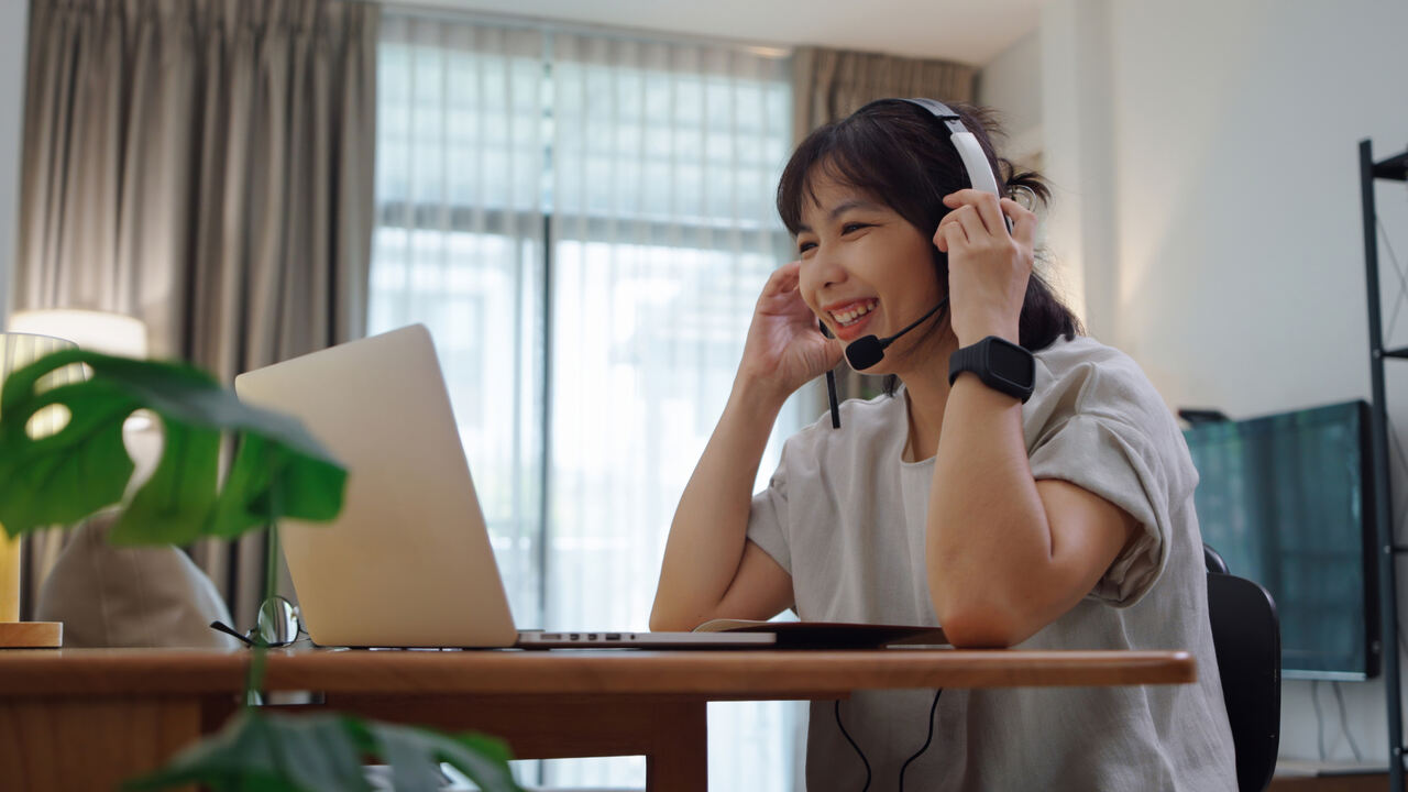 Mulher em home office usando notebook e headset, ilustrando consumo de largura de banda em videochamadas