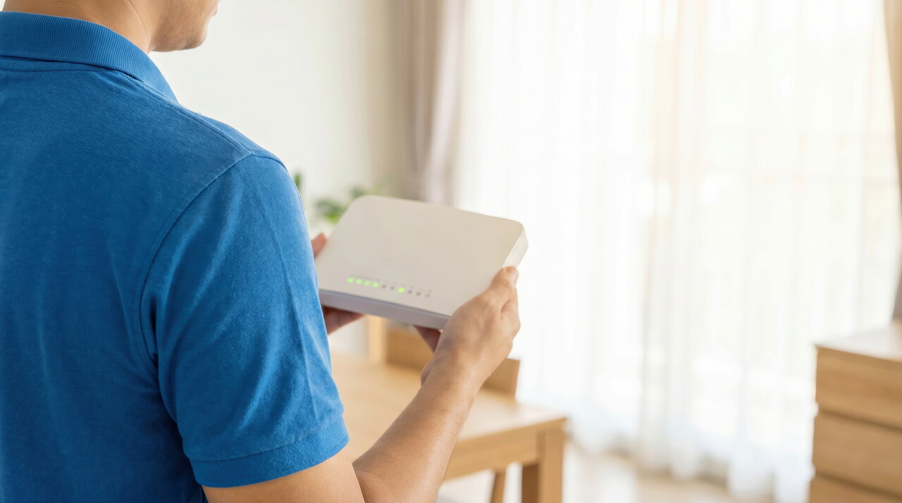 Pessoa segurando um modem de internet em ambiente interno, representando configuração de rede, conexão Wi-Fi e endereço IP do modem.